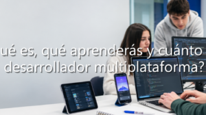 Estudiantes de DAM programando código en ordenador y dispositivos móviles para desarrollo multiplataforma.