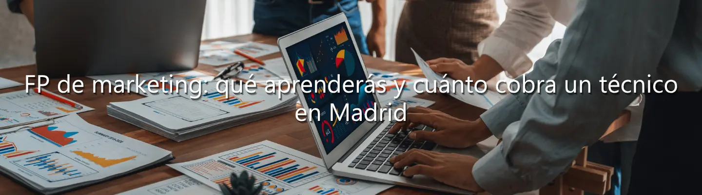 Estudiantes de FP de marketing analizando gráficos de datos en un portátil y documentos impresos sobre un escritorio.